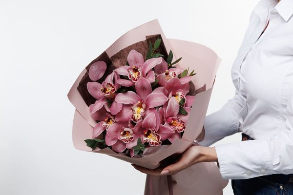 Krásne veľké kvety orchidei sú doplnené jemnými vetvičkami eukalyptu a decentným dekoračným papierom v ružovom odtieni.
