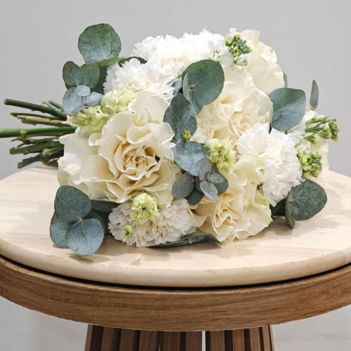 Bohato viazaná svadobná kytica v bielych tónoch, ktorá vyniká jemnou textúrou kvetov a modernou zeleňou.