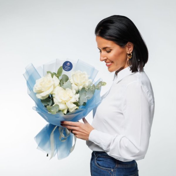 Minimalistická kytica s tromi bielymi francúzskych ružami a vetvičkami eukalyptu v modrom dizajnovom balení.