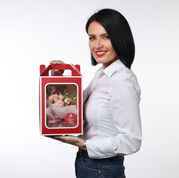 Elegantný červený darčekový box s priehľadným okienkom, v ktorom je umiestnená jemná kytica ružových kvetov.