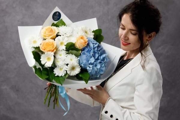 Jemná kytica s modrou hortenziou, broskyňovými ružami, bielymi gerberami a chryzantémami v elegantnom bielom dekoračnom papieri.