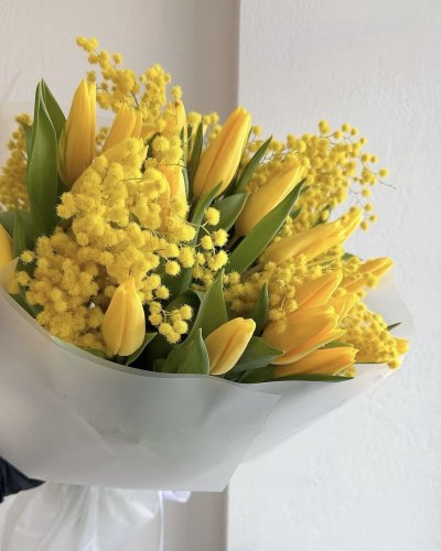 Žiarivá žltá farba mimózy a tulipánov kontrastuje s jemným, mierne priehľadným, bielym dekoračným papierom.