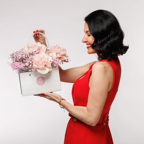 Nežný darček, ktorý zaručene poteší.  Ružové kvety sú aranžované do boxu v tvare malej bielej kabelky.